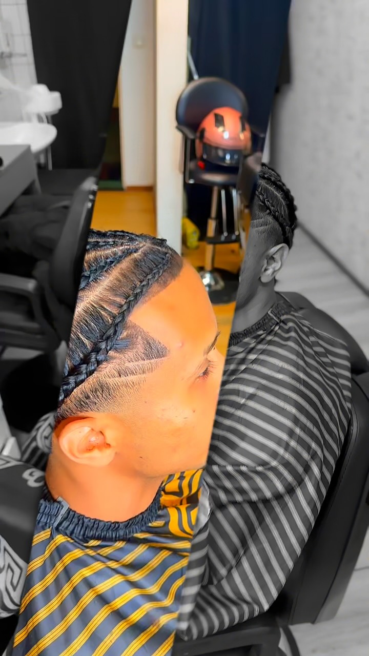 Gevlochten cornrows met een fade, klant in een zwart-gouden kapmantel